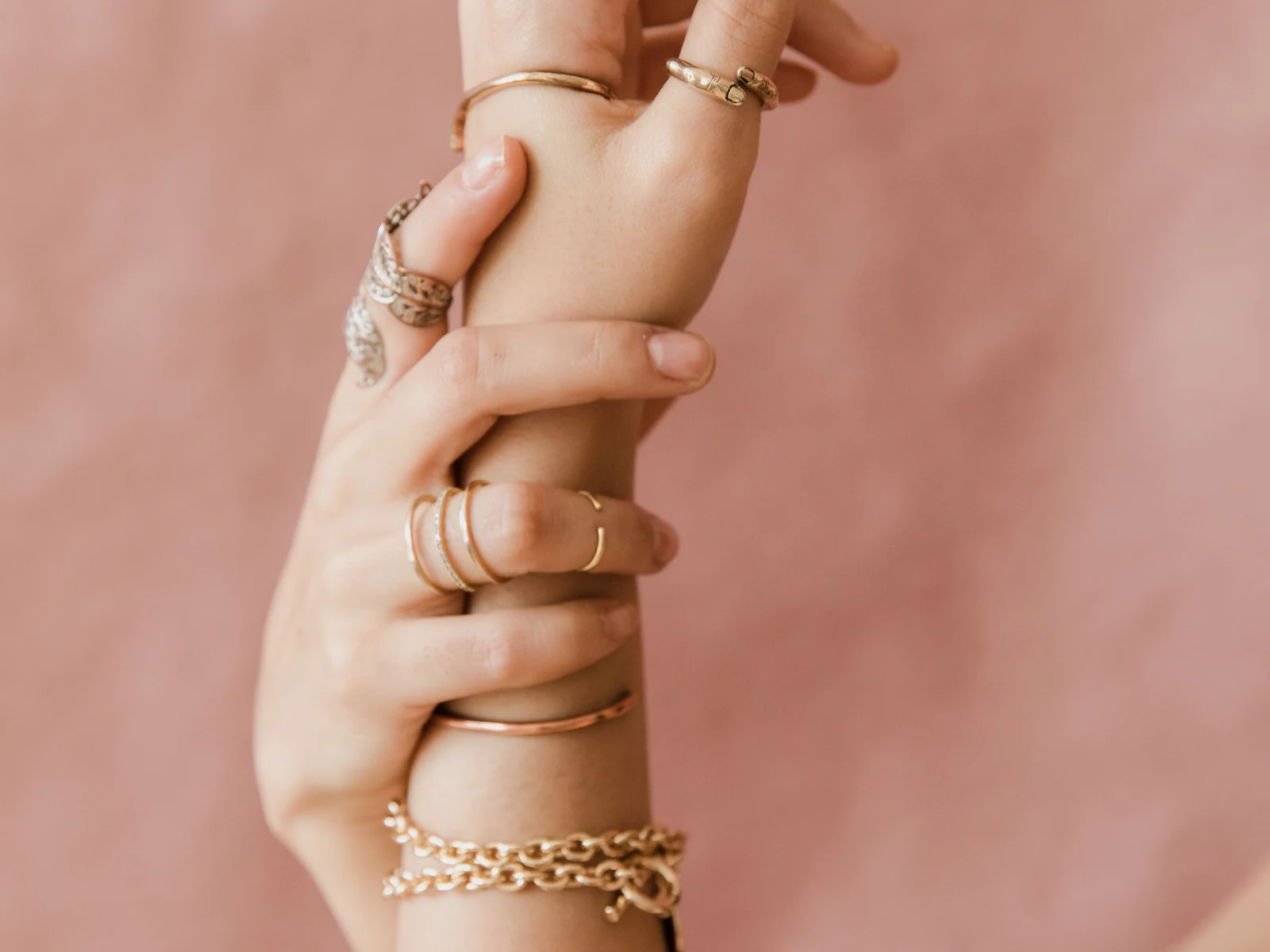 Stackable gold rings and chain bracelet gift idea Stacked gold rings and a gold chain bracelet worn together on a woman's hands