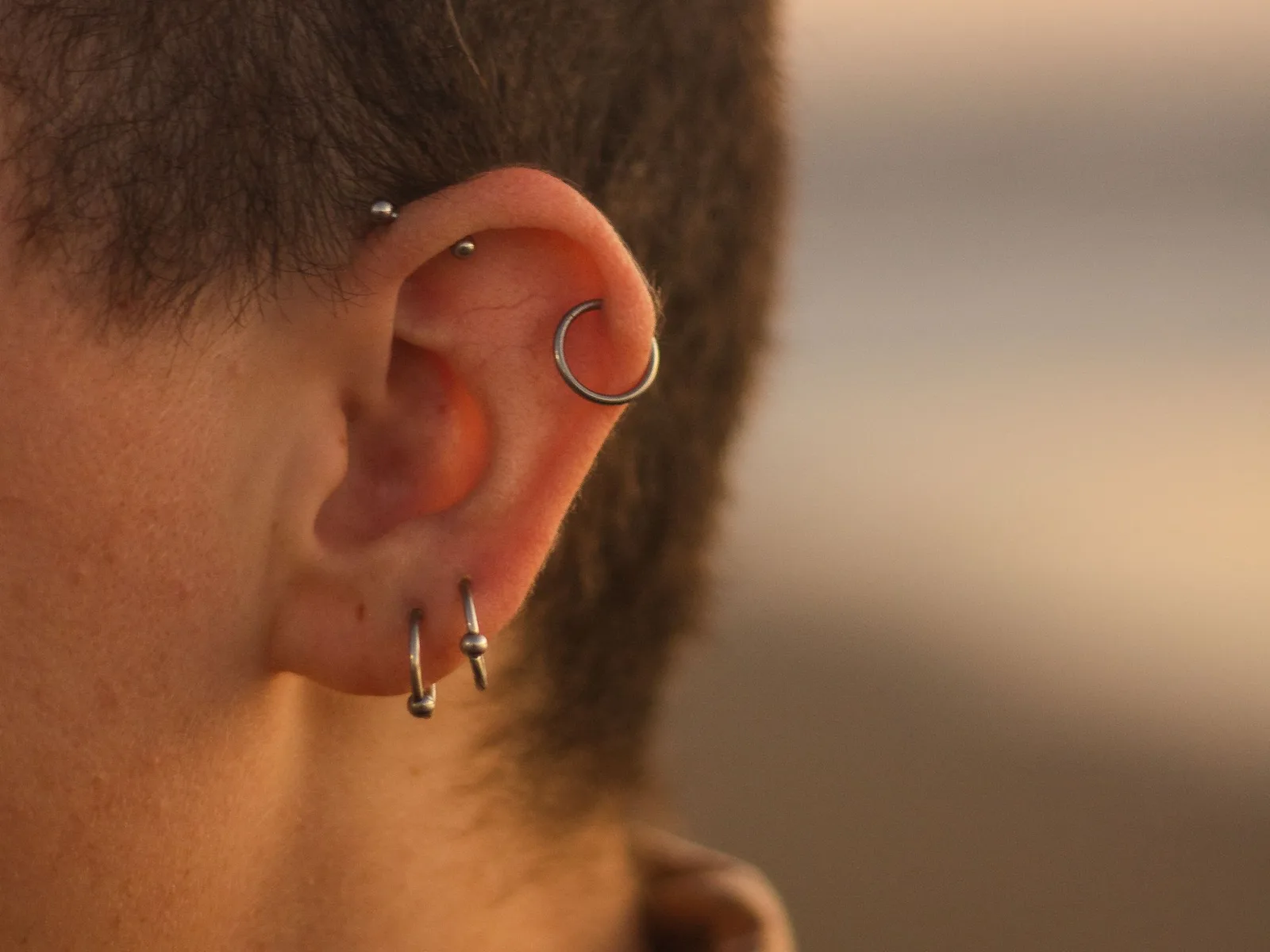 Ear with two small hoops in the lobe, a cartilage hoop on the helix and two studs on the upper ear