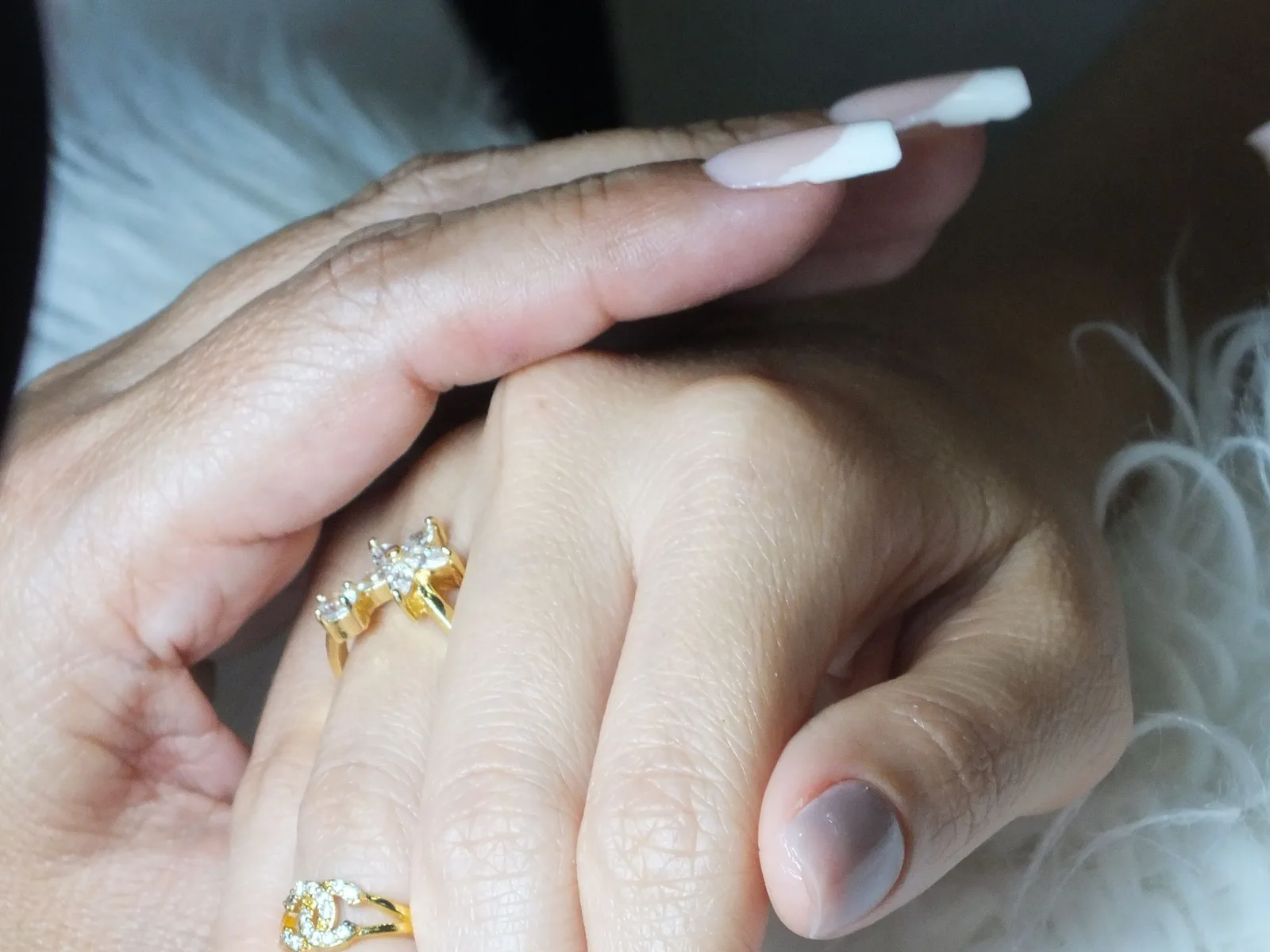 Manicured hands wearing several gold rings