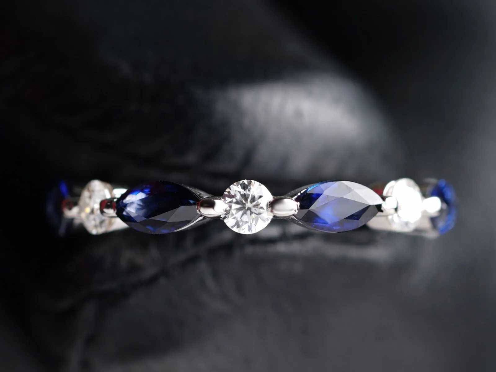 Close-up of a band set with marquise blue sapphires alternating with round white diamonds